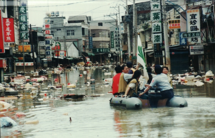 一九九四年八月四日,岡山地區大淹水,六個里積水盈尺,水面家具、垃圾、動物屍體四處漂流,涂茂興(左二)與志工乘橡皮艇協助救災中心,將災民安頓在嘉興國小活動中心。(圖片/涂茂興提供)