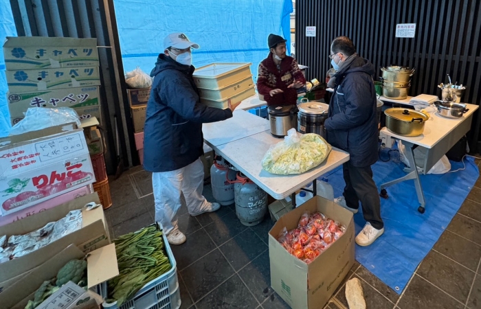 會館志工也是承擔每日熱食發放的石河直先生(中)告知志工,「農家友善鄉親送來很多的蔬菜,有需要都可以使用。」(圖:日本真善美志工)