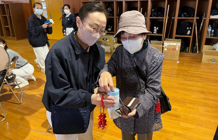 若林美惠子臨走前,阿嬤拿出一張千元日鈔投入竹筒:「我也要做好事。」(攝影:中山慧珊)
