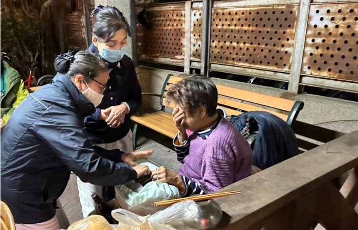 在五股黃昏市場旁,六十八歲的阿嬤(右),腰椎受傷,老公往生,女兒各自都有家庭,無力負擔她,志工給的物資及油飯倍感暖心,她邊吃紅麴飯邊流淚,也感恩志工送物資來。(攝影:劉瑞香,地點:五股黃昏市場,日期:2023/12/18)