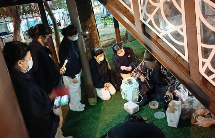 六合公園溜滑梯下,六十八歲的陳先生腳受傷過,較無力氣,流浪已三十年。志工送上熱食,暖語膚慰。(攝影:吳家慶,地點:六合公園,日期:2023/12/18)